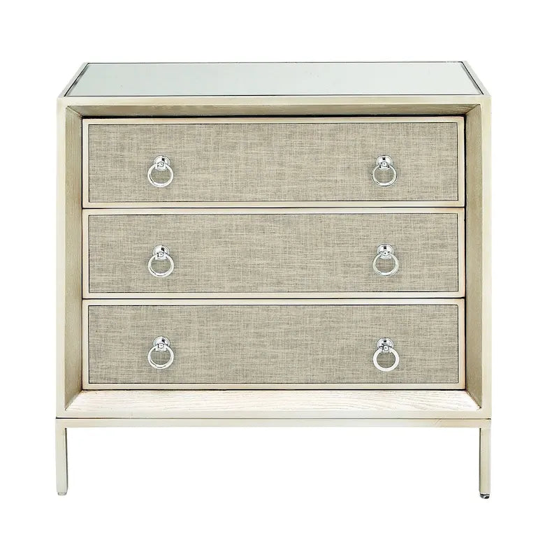 Commode 3 tiroirs en bois beige, avec finition capitonnée, plateau miroir et poignées anneaux.